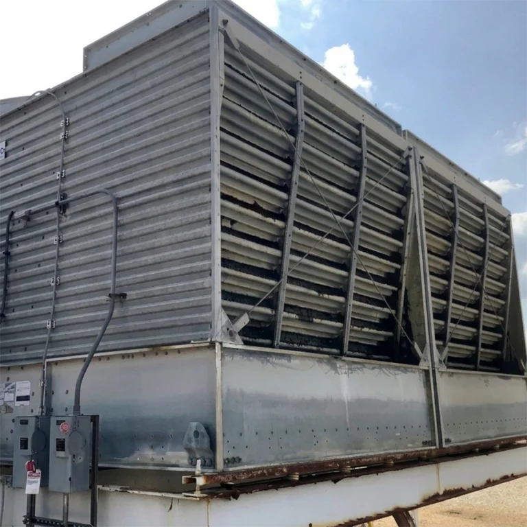 Large industrial HVAC cooling tower in need of replacement with rusted panels and vents, mounted on a platform.